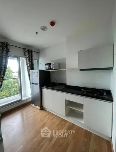 Modern kitchen with sleek cabinets, gas stove, and balcony view in a stylish apartment.