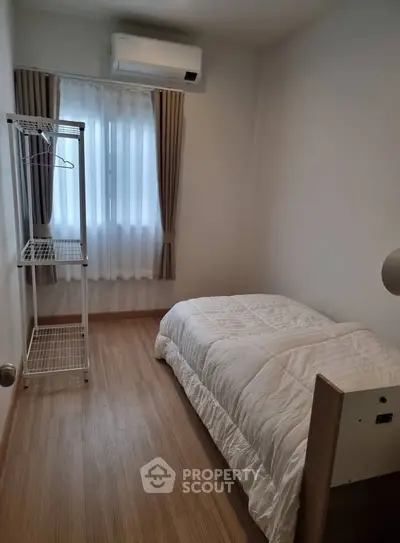Cozy minimalist bedroom with wooden flooring and natural light