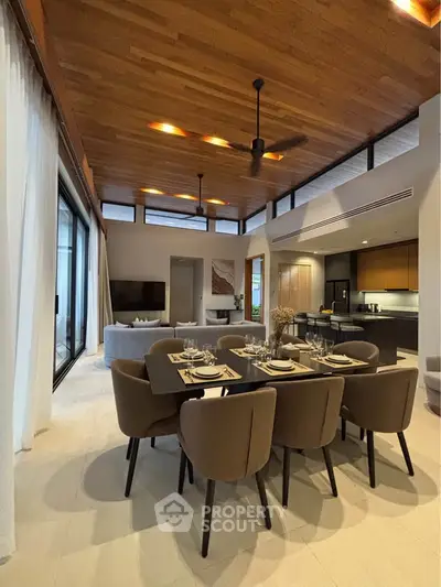 Luxurious open-plan living and dining area with modern furnishings and wooden ceiling.