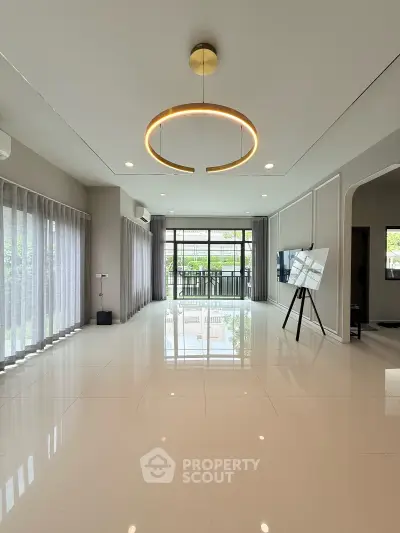 Spacious modern living room with elegant lighting and large windows opening to a balcony.