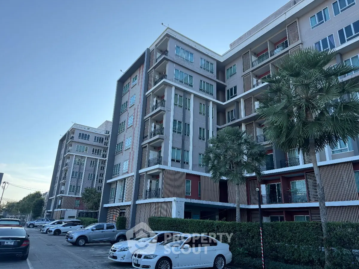 Modern apartment building with parking and lush greenery, showcasing urban living.
