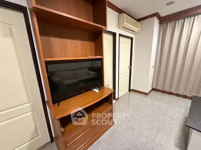 Cozy living room with built-in wooden TV cabinet and air conditioning unit.