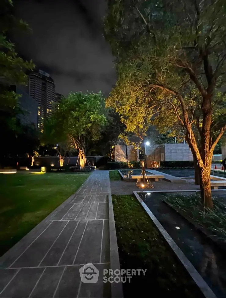 Luxurious garden pathway with ambient lighting in a modern residential complex at night.