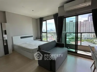 Modern bedroom with city view and balcony access in high-rise apartment.