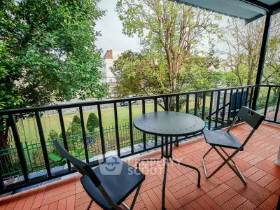 Charming balcony with outdoor seating and lush garden view, perfect for relaxation.