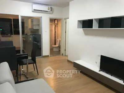 Modern living room with open layout and sleek furniture, featuring a view into a compact bathroom.