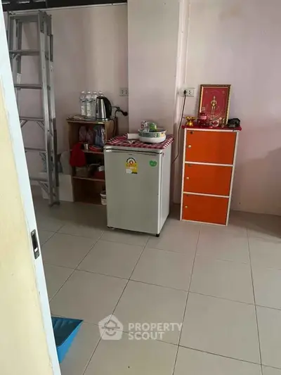 Compact kitchen area with mini fridge and storage solutions