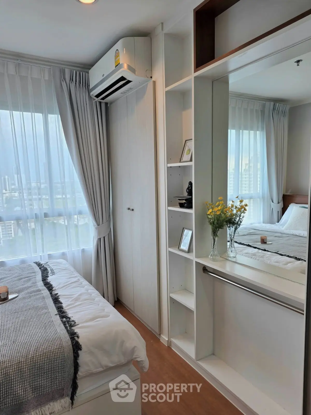 Modern bedroom with large window, built-in shelves, and air conditioning unit in a high-rise apartment.