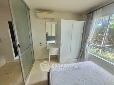 Bright bedroom with large window, white furniture, and garden view