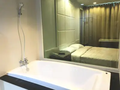 Modern bathroom with bathtub and glass wall overlooking a cozy bedroom