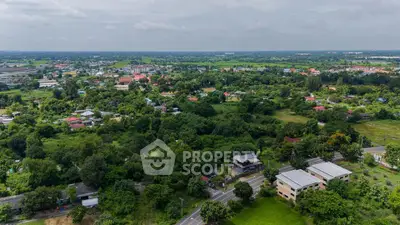 Scenic aerial view of lush green landscape with residential homes and open fields.