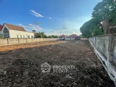 Spacious vacant land with potential for development, surrounded by residential buildings and lush greenery.