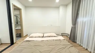 Modern minimalist bedroom with cozy bedding and ensuite bathroom in stylish apartment.