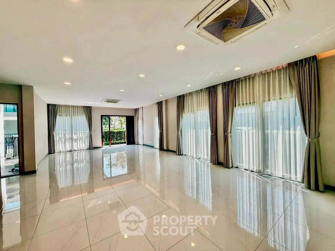 Spacious modern living room with large windows and polished tile flooring