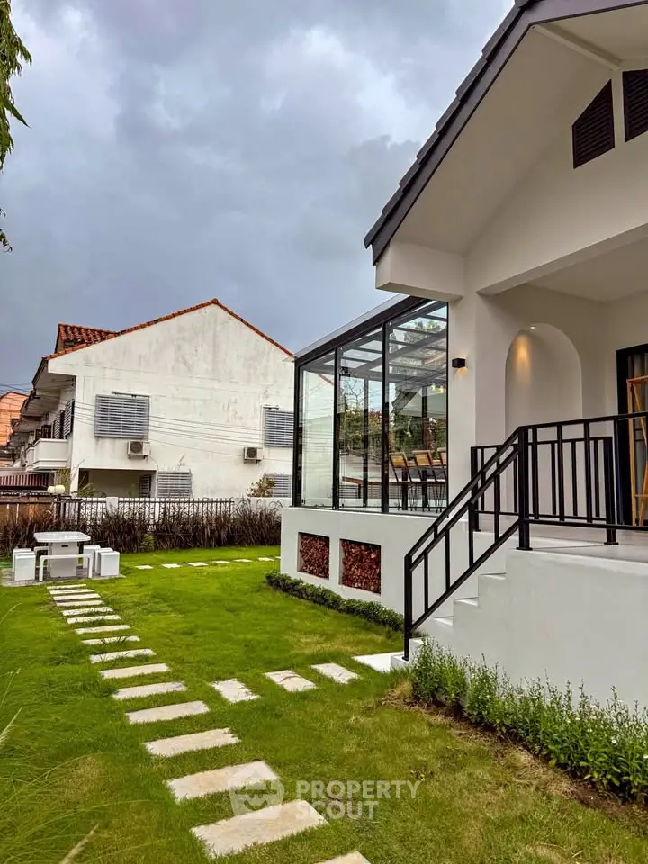 Charming modern house with glass extension and lush green garden, perfect for family living.