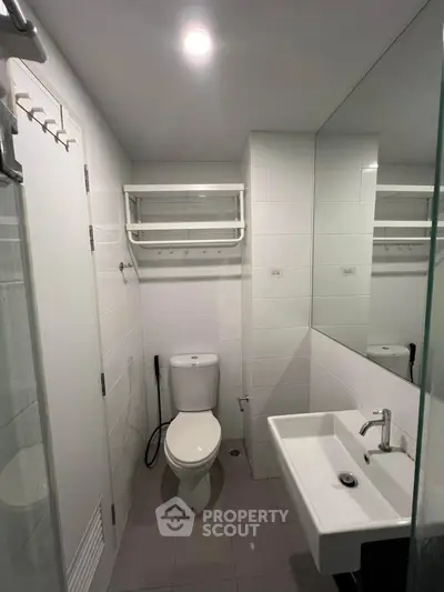Modern bathroom with sleek fixtures and wall-mounted sink in a compact layout.