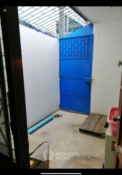 Secure outdoor space with blue metal gate and concrete flooring, ideal for storage or utility use.