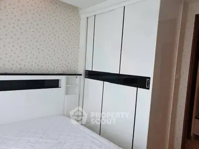 Modern bedroom with sleek white wardrobe and stylish wallpaper