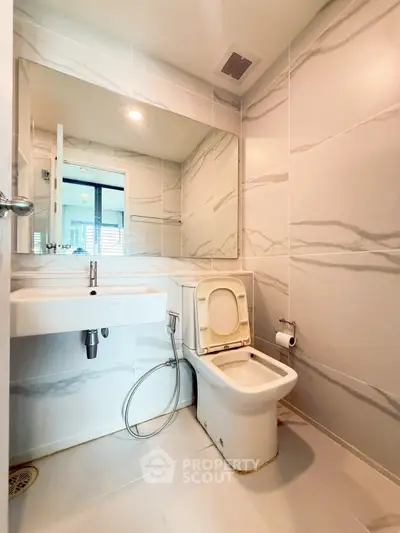 Modern bathroom with sleek design, featuring a large mirror and elegant tile work.