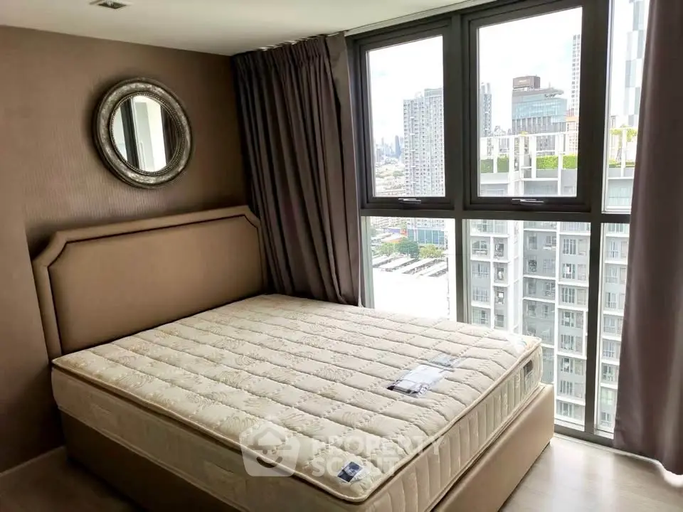 Modern bedroom with large window offering stunning city views in a high-rise apartment.