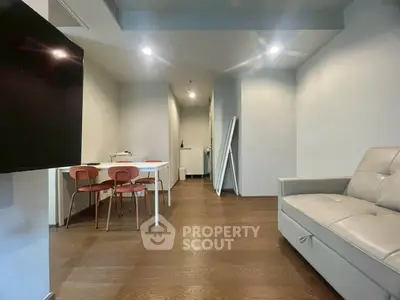 Modern living room with sleek furniture and dining area, featuring wooden flooring and contemporary lighting.