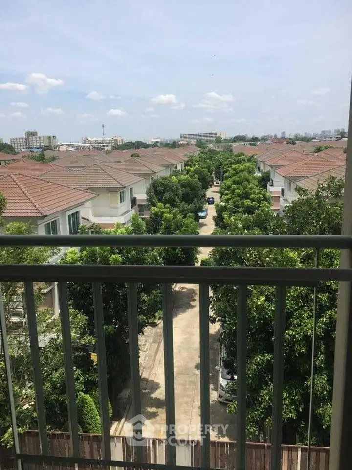 Scenic view from balcony overlooking suburban neighborhood with lush greenery and clear skies.