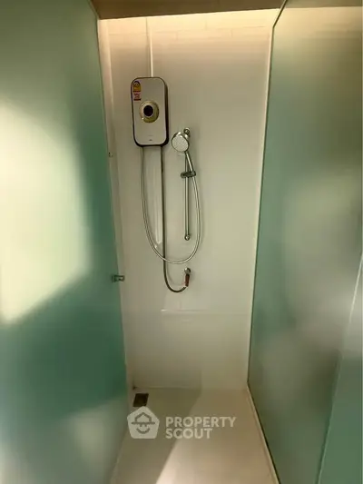Modern shower area with glass panels and sleek showerhead in minimalist bathroom.