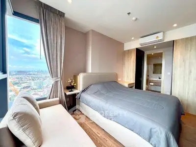 Modern bedroom with city view, featuring a cozy bed and stylish decor in a high-rise apartment.