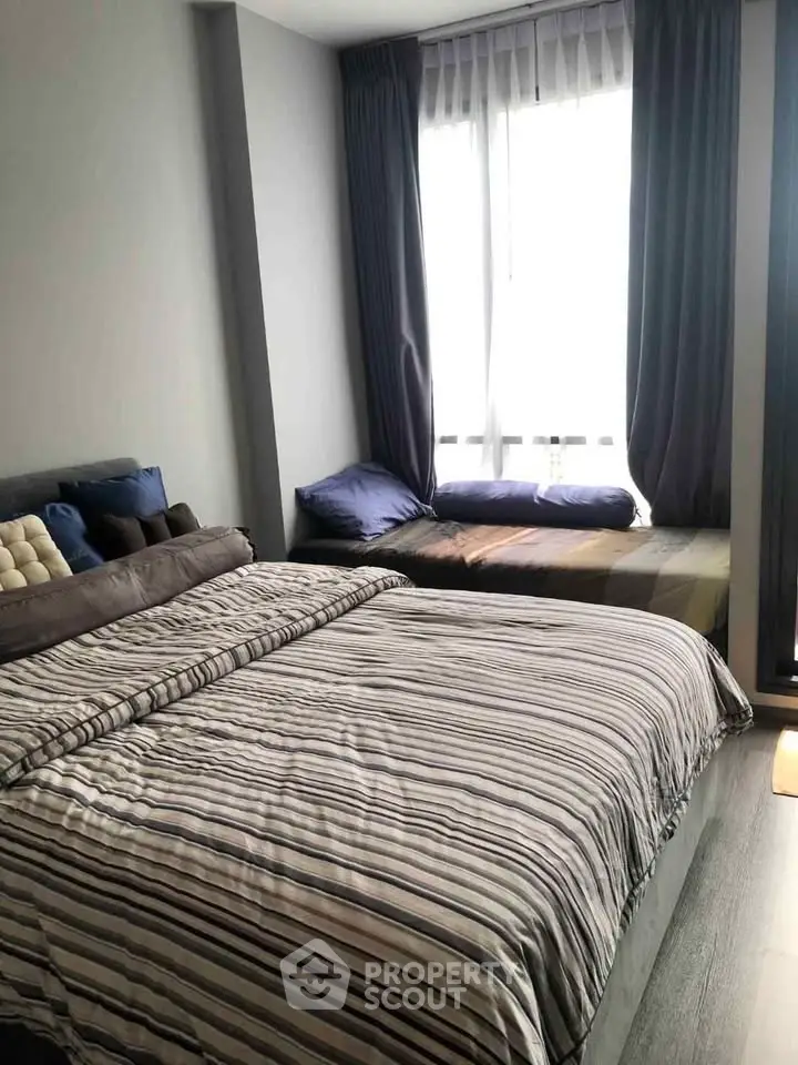 Cozy bedroom with striped bedding and large window for natural light.
