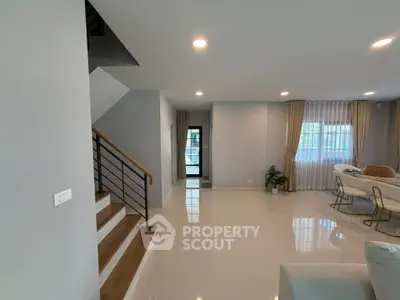 Modern open-plan living area with sleek staircase and dining space