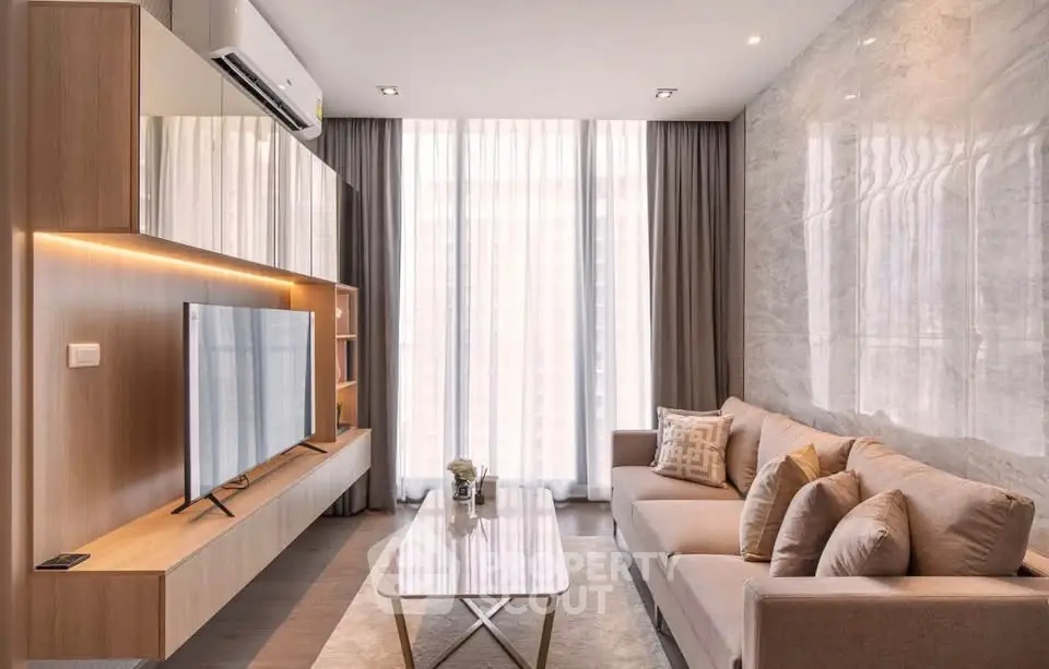 Modern living room with sleek furniture and large windows, featuring a stylish TV unit and cozy sofa.
