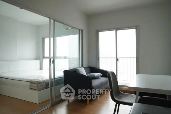 Modern apartment with cozy living area and bedroom separated by glass doors.