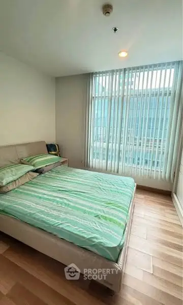 Bright and cozy bedroom with large window and modern decor.
