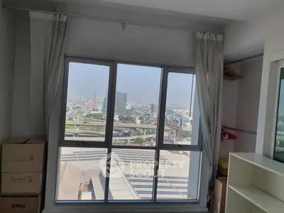 Bright room with large window offering panoramic city view, ideal for urban living.