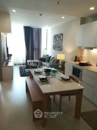 Modern open-layout living room and kitchen with stylish decor and natural light.