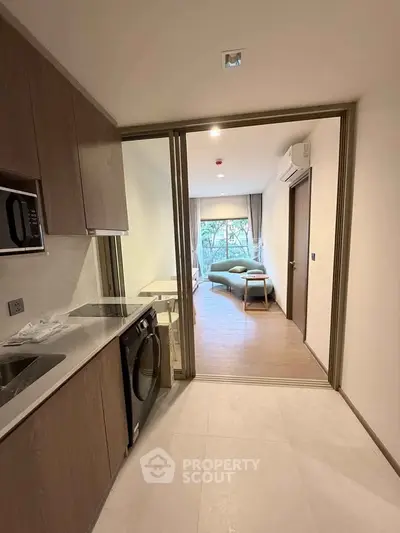 Modern apartment interior with kitchen and living room, featuring sleek design and natural light.