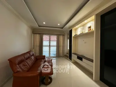 Spacious living room with elegant leather sofa and modern entertainment unit, featuring large windows for natural light.