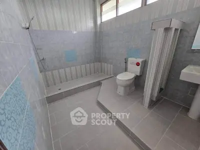 Spacious modern bathroom with sleek tile design and elevated shower area.