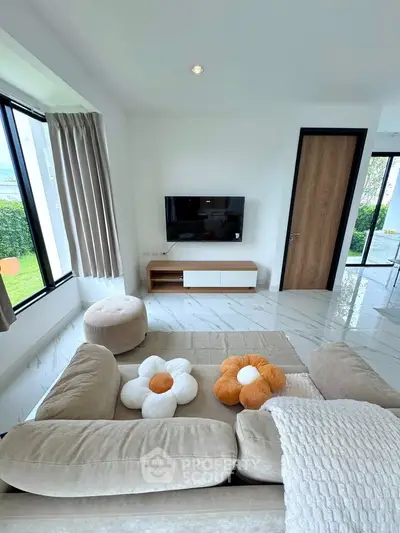 Modern living room with plush beige sofa, stylish decor, and wall-mounted TV, offering a cozy and inviting atmosphere.