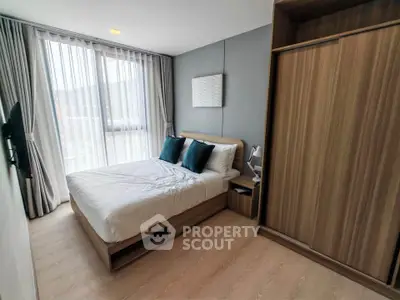 Modern bedroom with large window and wooden wardrobe in stylish apartment.