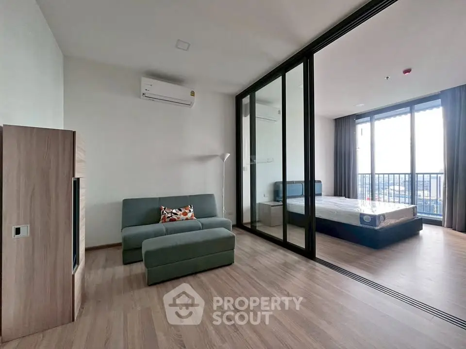 Modern apartment with spacious living room and bedroom, featuring large windows and a balcony with city views.