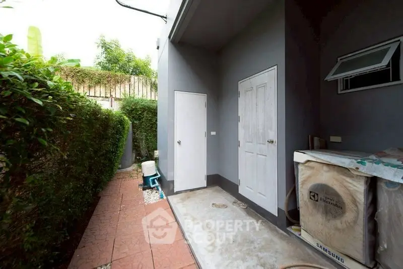 Charming outdoor area with lush greenery and utility space, perfect for gardening enthusiasts.
