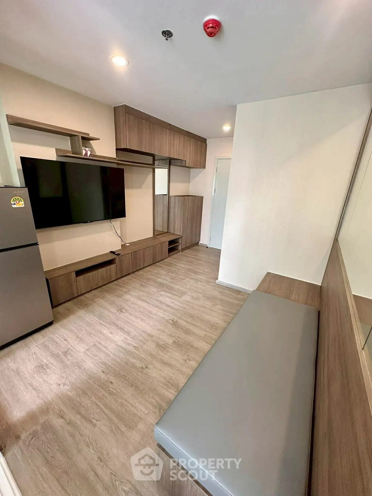 Modern living room with sleek wooden furniture and mounted TV in a cozy apartment.