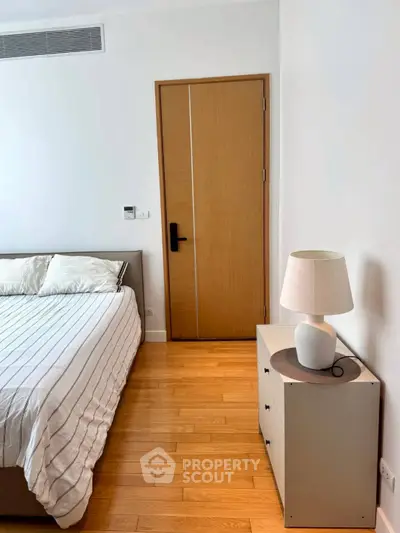 Modern bedroom with wooden flooring and stylish furniture in a cozy apartment.