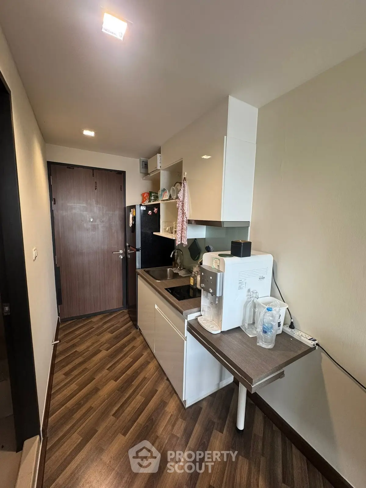 Modern compact kitchen with sleek cabinetry and wood flooring in a cozy apartment.