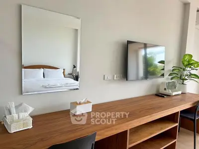 Modern bedroom with sleek wooden desk, wall-mounted TV, and stylish decor.