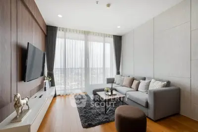 Modern living room with sleek furniture and large windows offering natural light and city views.