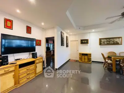 Spacious living room with modern decor and dining area, featuring a large wall-mounted TV and elegant furniture.