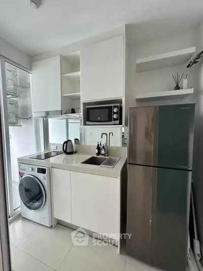 Modern compact kitchen with sleek appliances and washing machine in a stylish apartment.