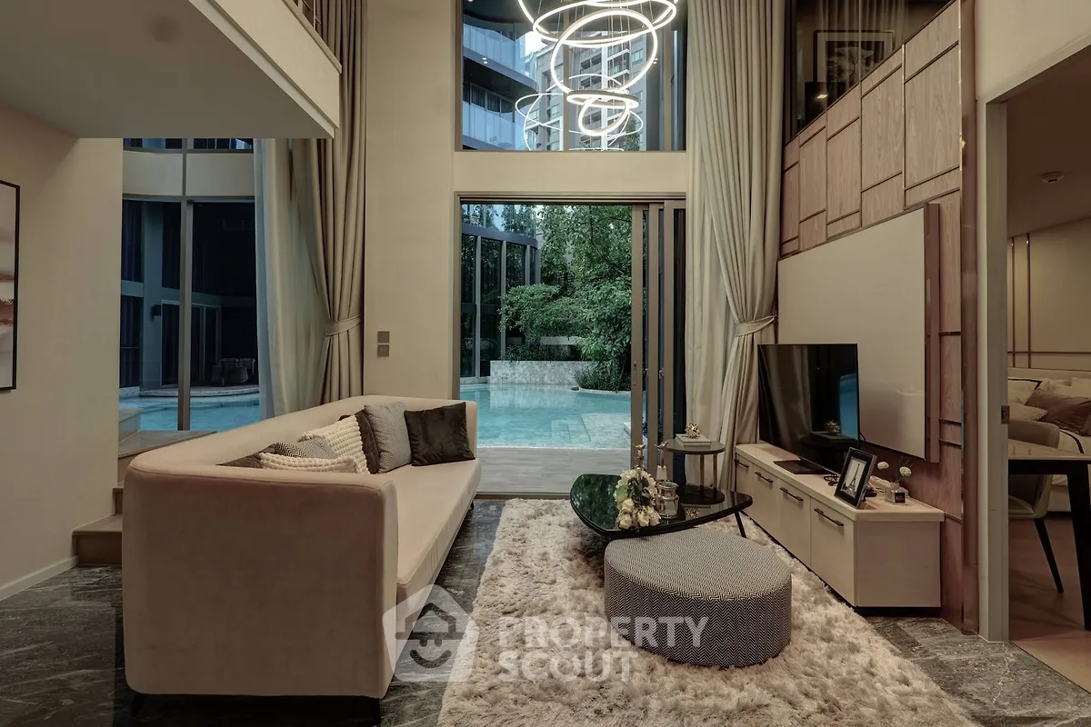 Luxurious living room with modern decor and pool view, featuring elegant lighting and plush furnishings.